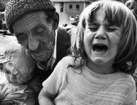 مسن بوسني يحمل حفيدته بعد رحلة طويلة قطعوها سيراً على الأقدام للوصول إلى مخيم لاجئين هرباً من إبادة الصرب