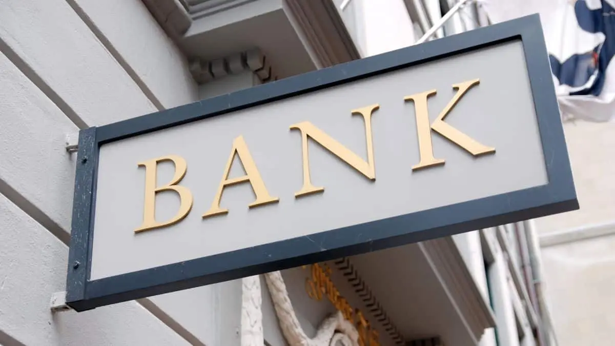 لافتة بنك تقليدي مكتوب عليها "BANK" مثبتة على واجهة مبنى، ترمز إلى النظام المصرفي القائم على الفائدة والخدمات المالية التقليدية